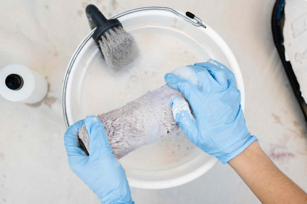 Verfroller met verf op oliebasis schoongemaakt in emmer met terpentine en handschoenen